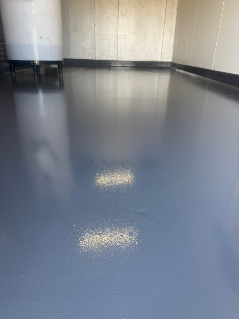 Commercial kitchen pump room after Legacy Industrial Coatings install showing continuous epoxy floor and coved wall base