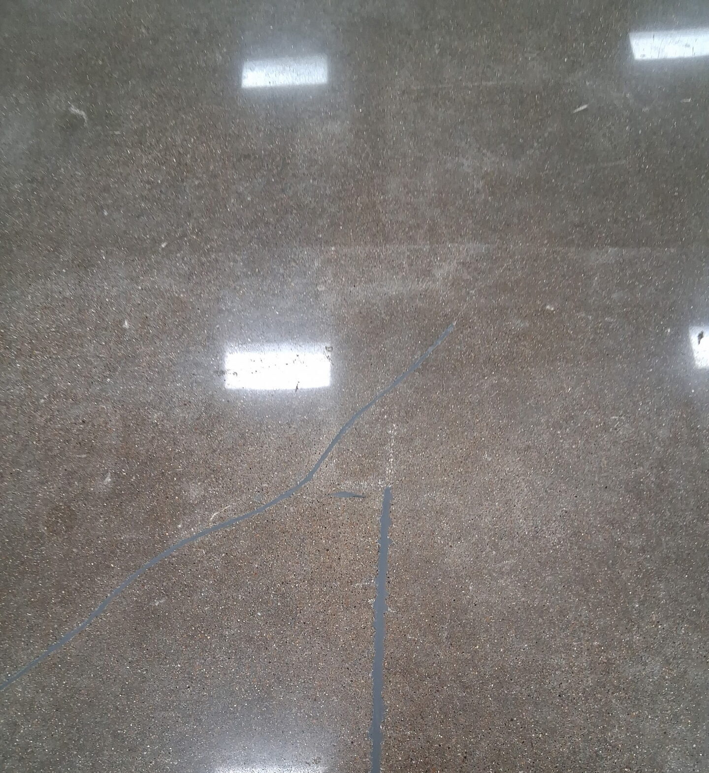 Polyurea crack filler integrated into the finished polished concrete slab — repairs grind flush with the surrounding floor