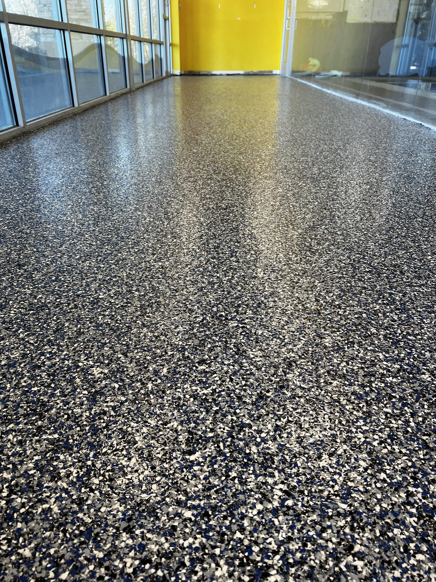 Completed swim school floor system — non-porous polyaspartic topcoat over polyurea base with custom flake blend matched to brand colors
