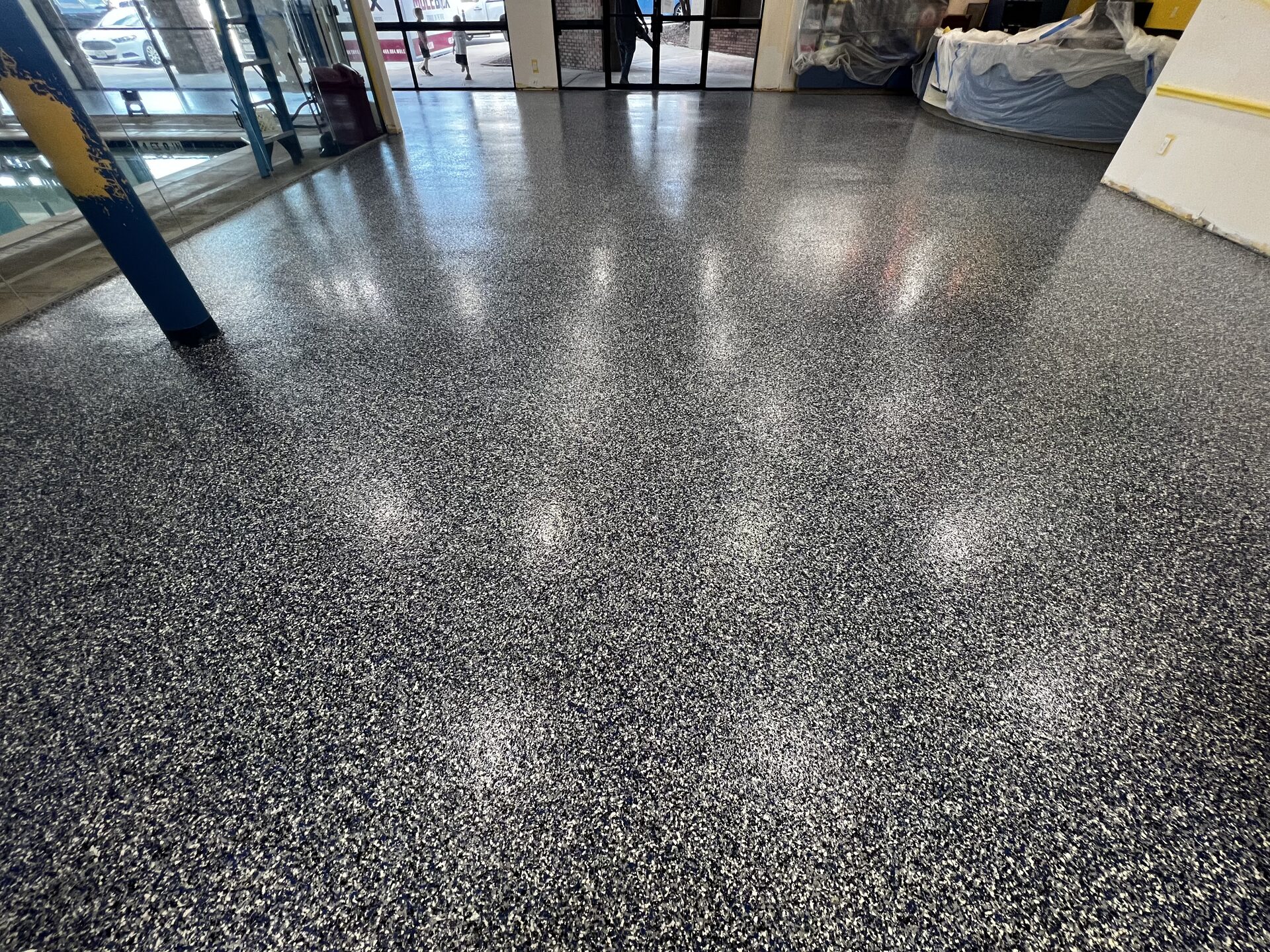 Wide view of completed polyurea polyaspartic flake floor in swim school pool deck area with reflective gloss and broadcast color flake