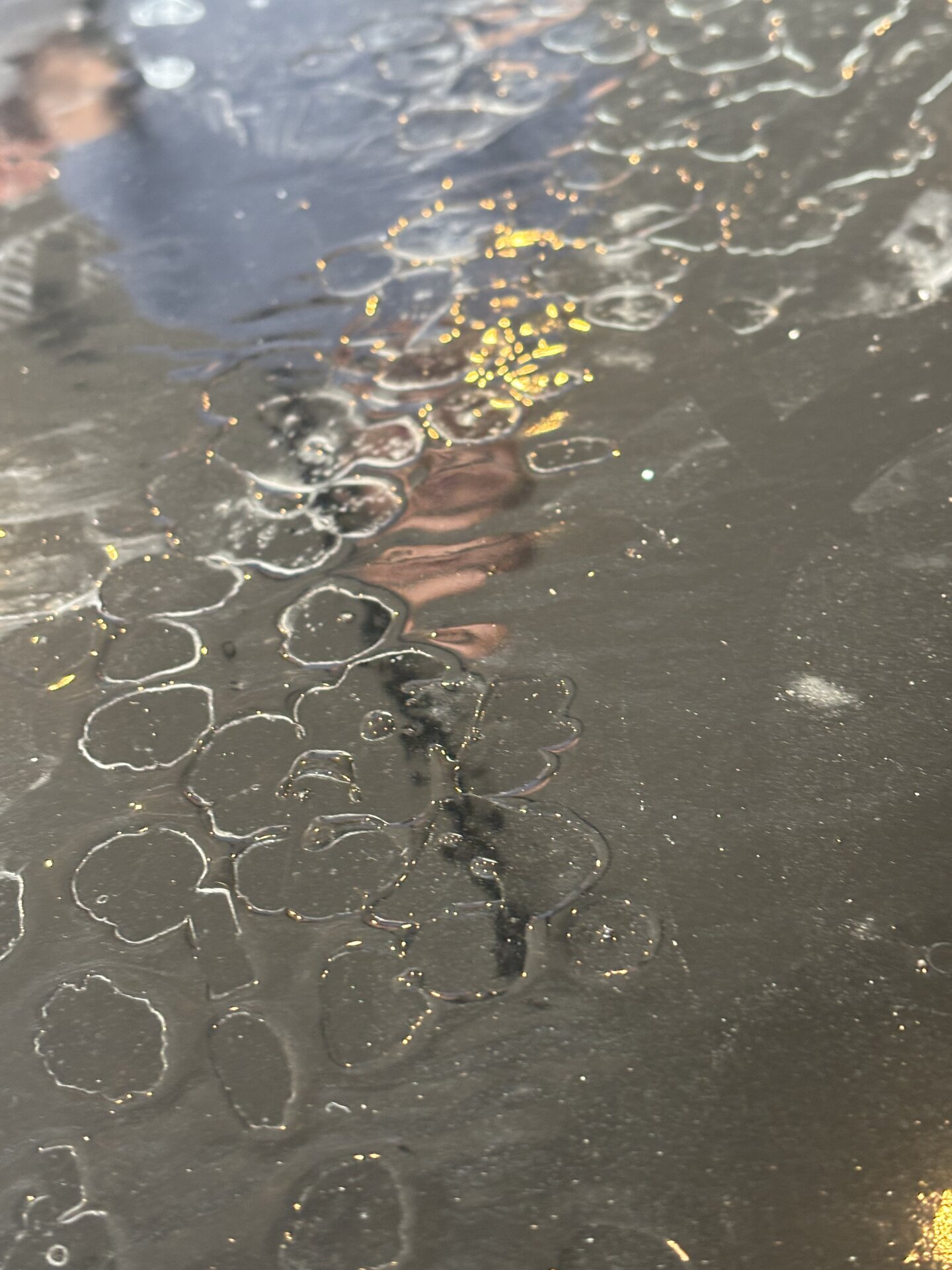 Peeling topcoat on a botched metallic epoxy floor in a luxury home garage before full removal