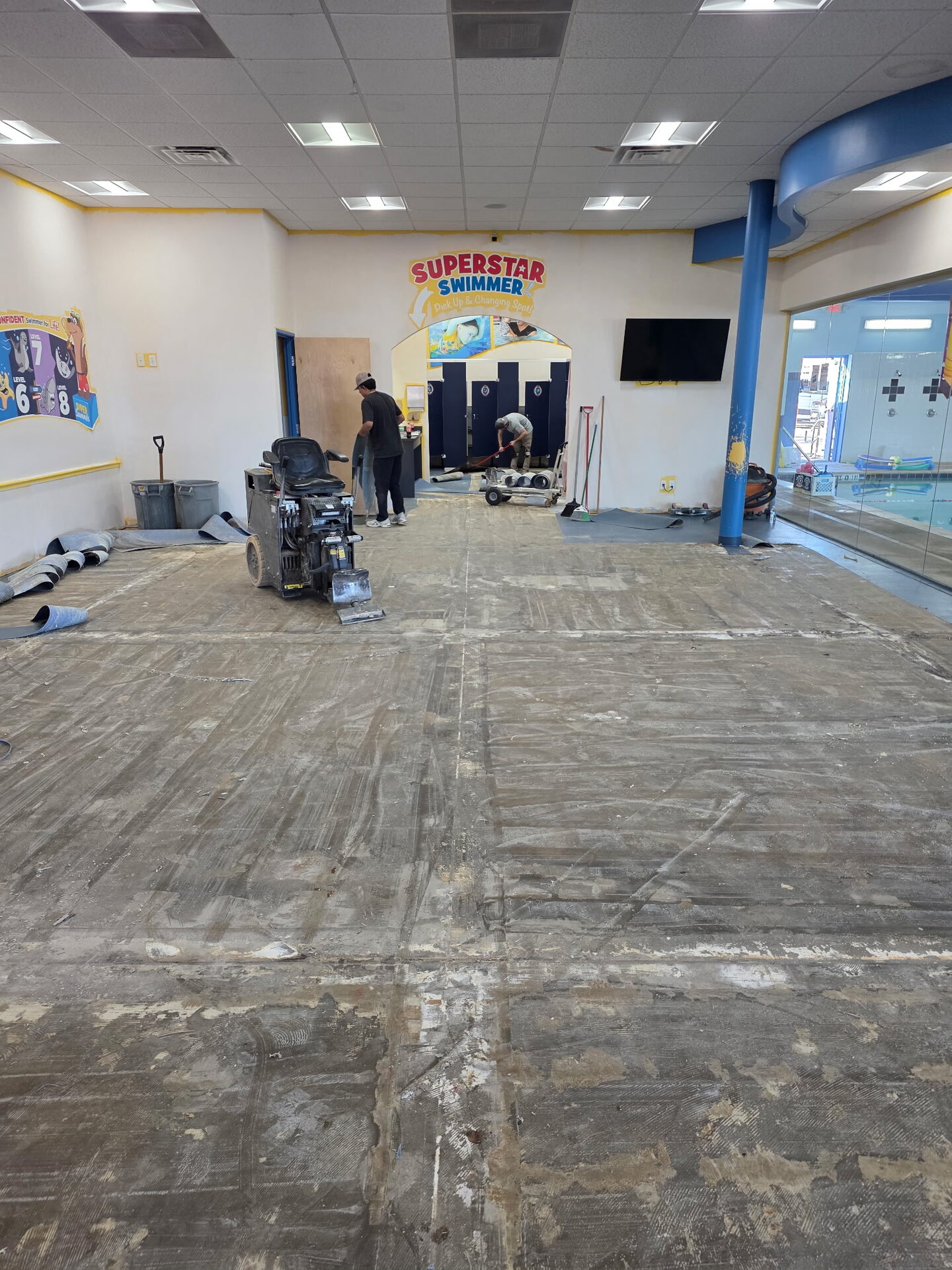 Existing tile floor in swim school changing area before tear-out, decontamination, and custom flake floor install
