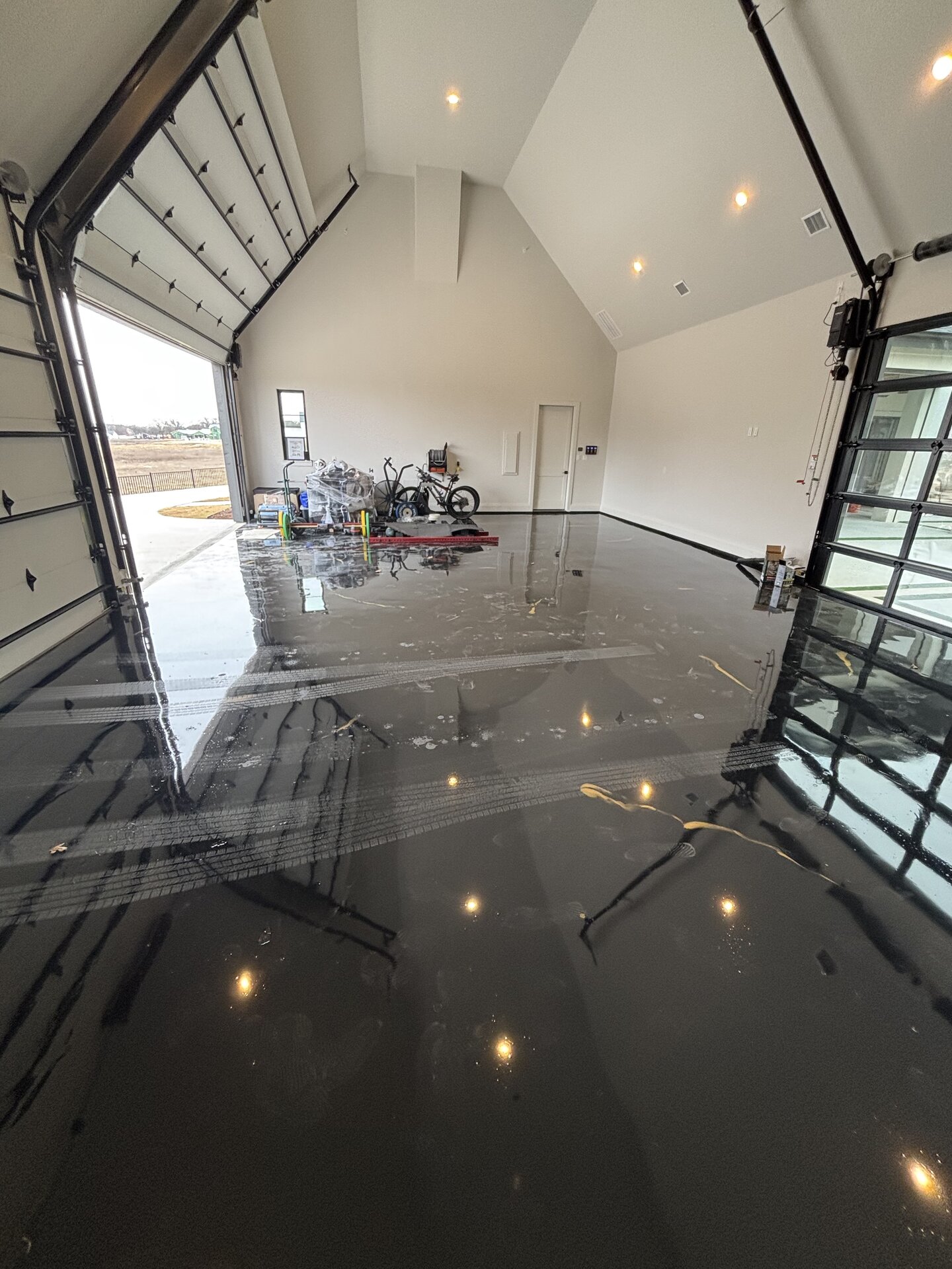 Sections of failed metallic coating lifting off the concrete in a luxury home garage prior to Legacy Industrial Coatings rebuild