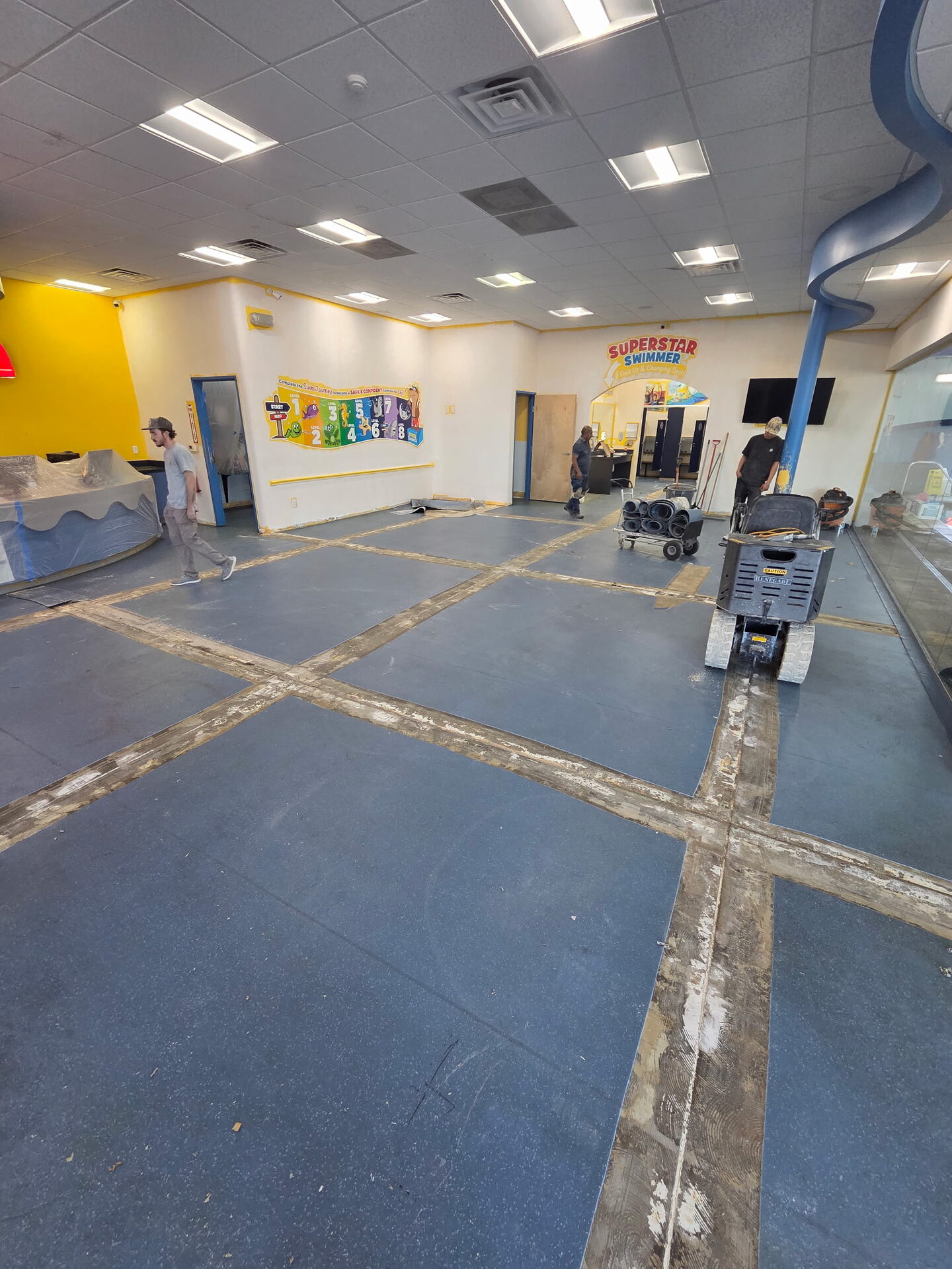Pre-installation condition of children's swim school floor showing the VCT tile system being removed