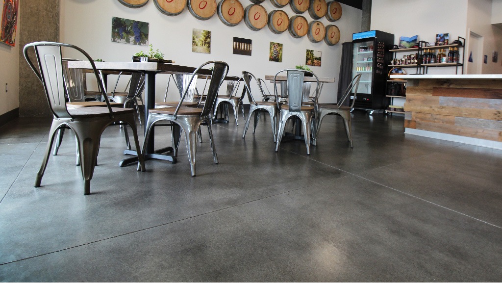 Close-up of sealed concrete floor in a commercial tasting room with metal chairs