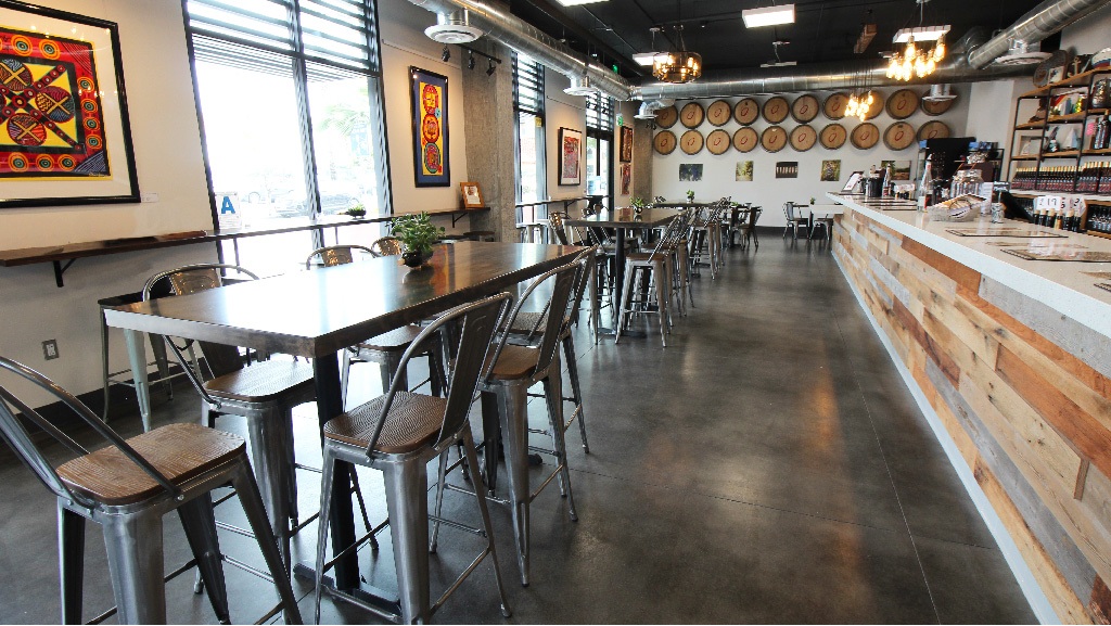 Sealed concrete floor in a brewery tasting room with bar seating and wine barrels