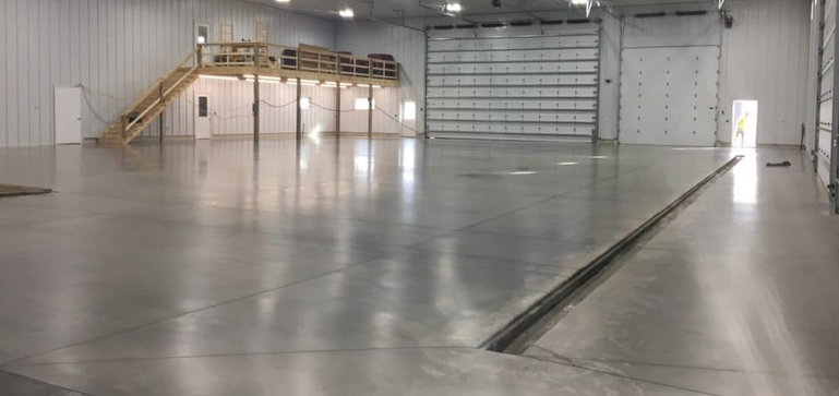 Large sealed concrete warehouse floor with overhead doors and mezzanine